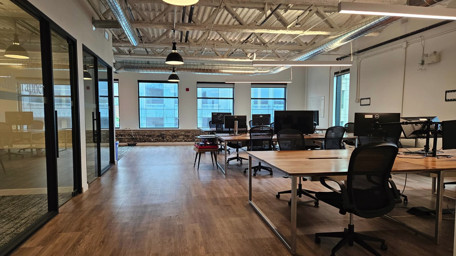 Open workroom floor with desks and glass meeting rooms
